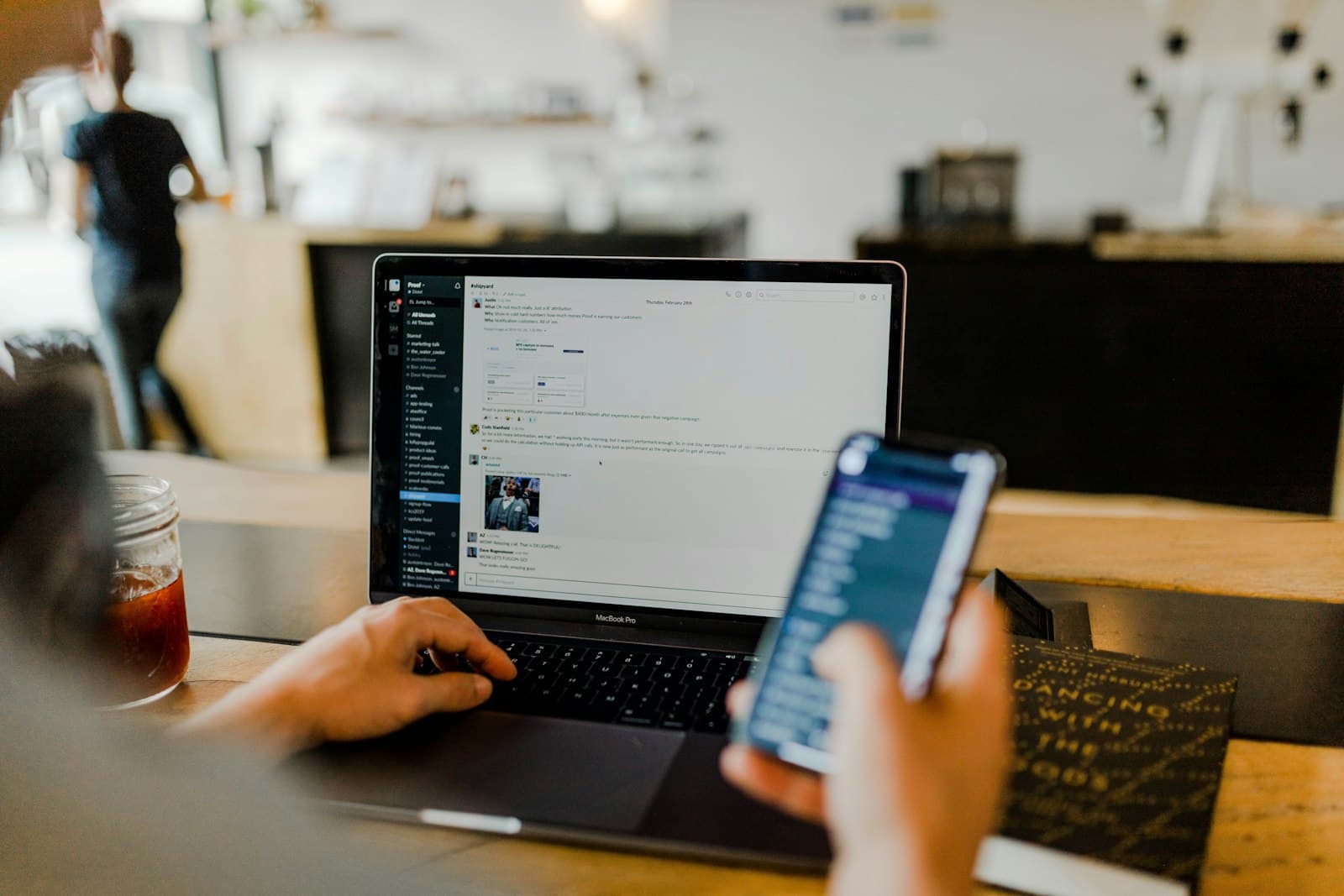Small-business owner working on a laptop while checking her phone