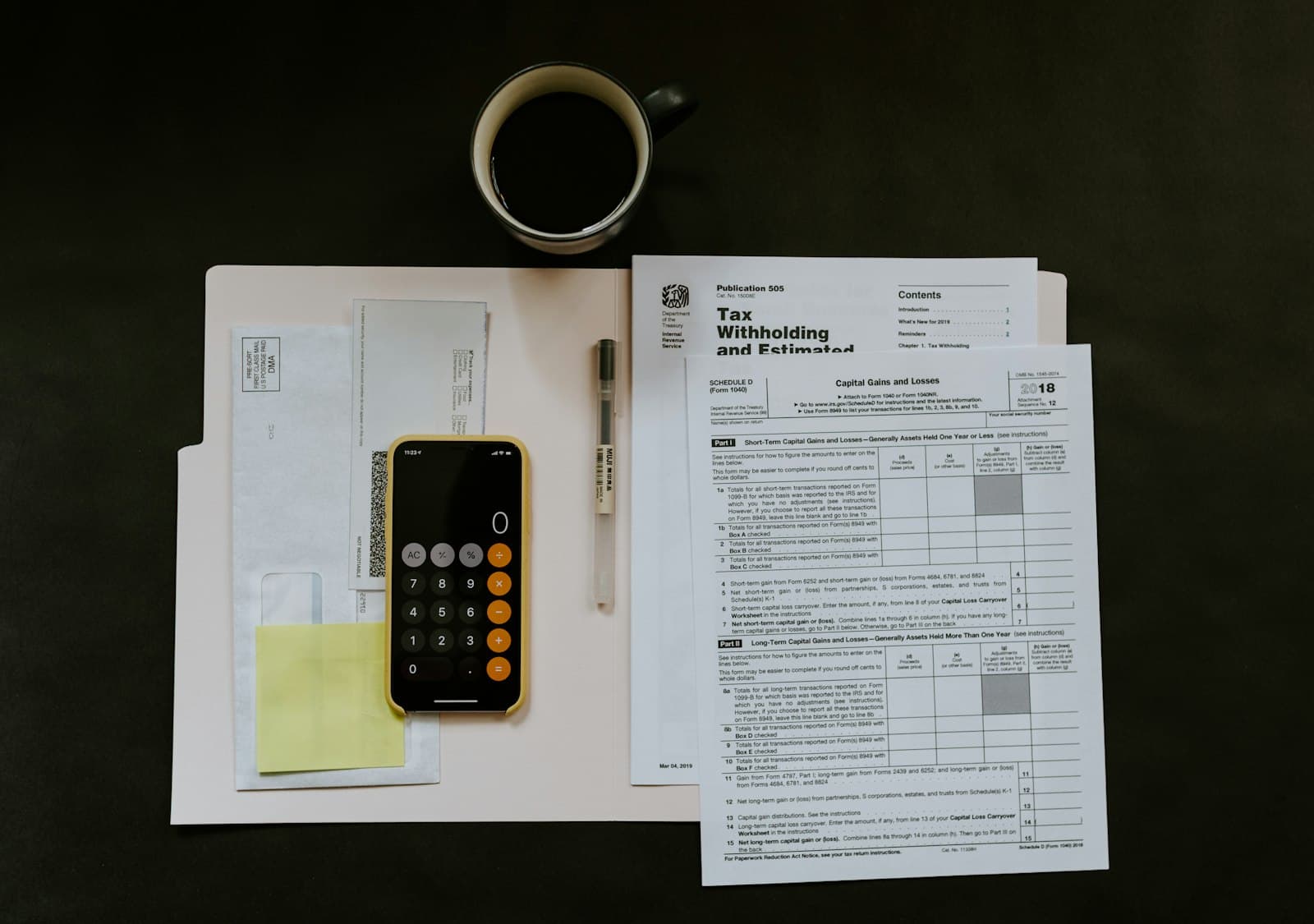 Tax forms, a calculator and a cup of coffee laid out on a desk