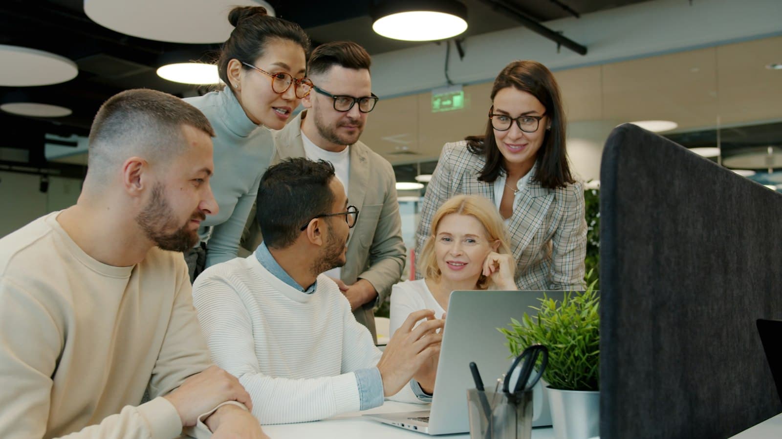 Team of colleagues gathered around a laptop at work
