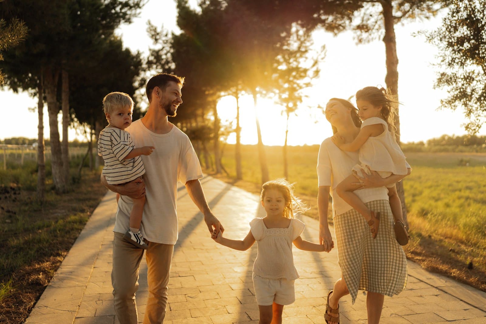 Parents walking hand in hand with their three young children at sunset