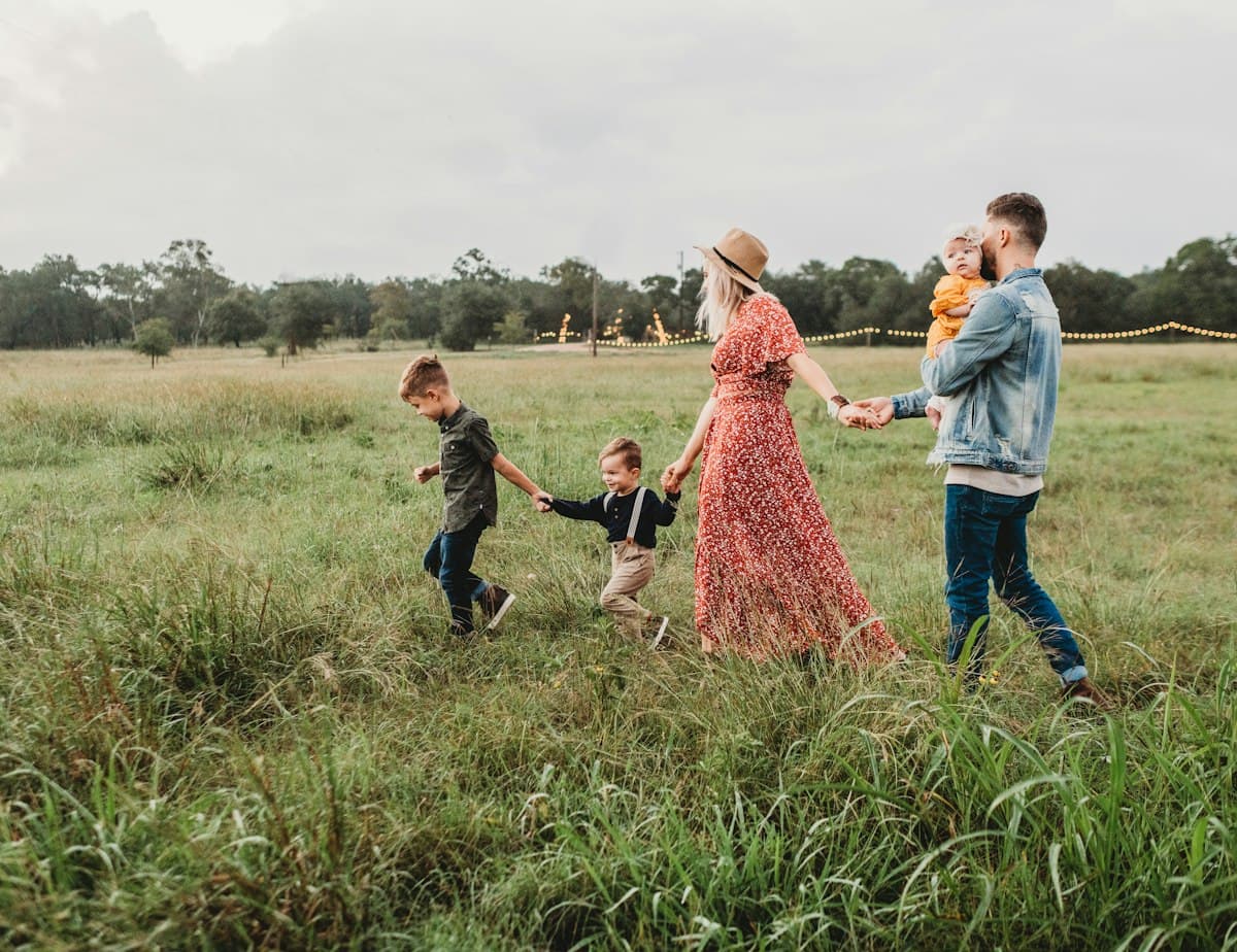 Family with young children walking together through a grassy field