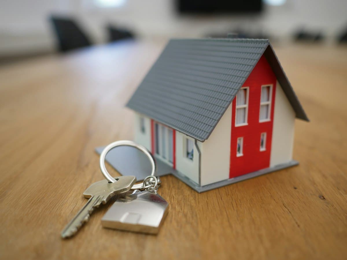 House keys resting beside a small model home on a wooden table