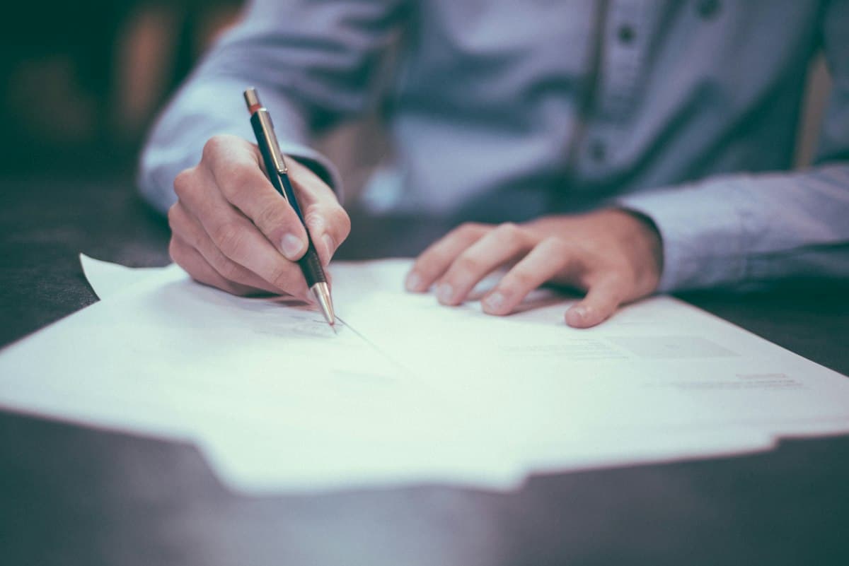 Professional carefully reviewing and signing documents at a desk