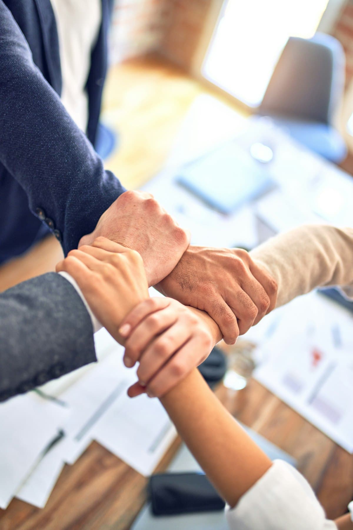 Team members stacking their hands together in a show of unity